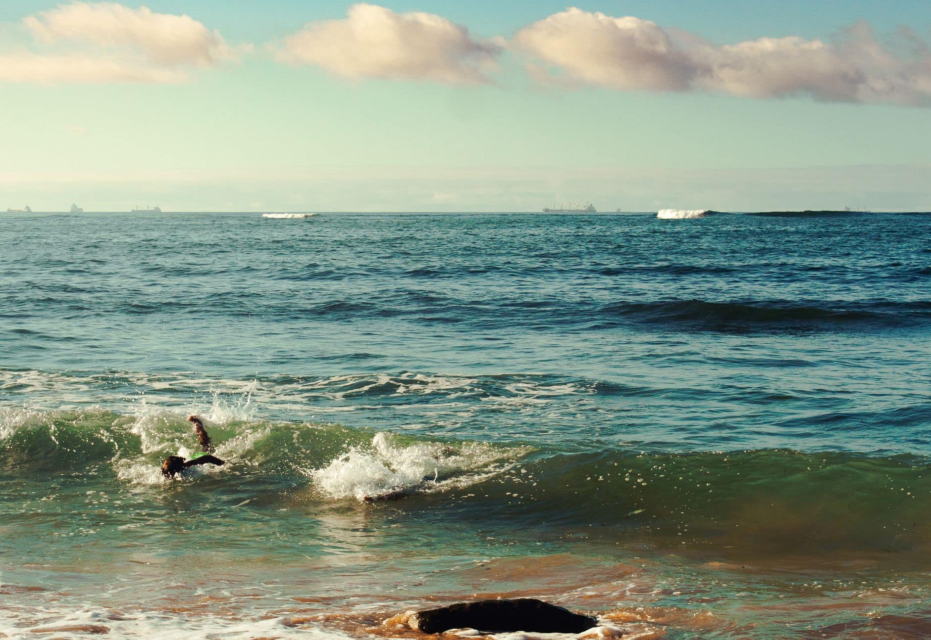 Tranquil ocean scene with swimmer enjoying the waves at Casablanca's beach under a clear blue sky.