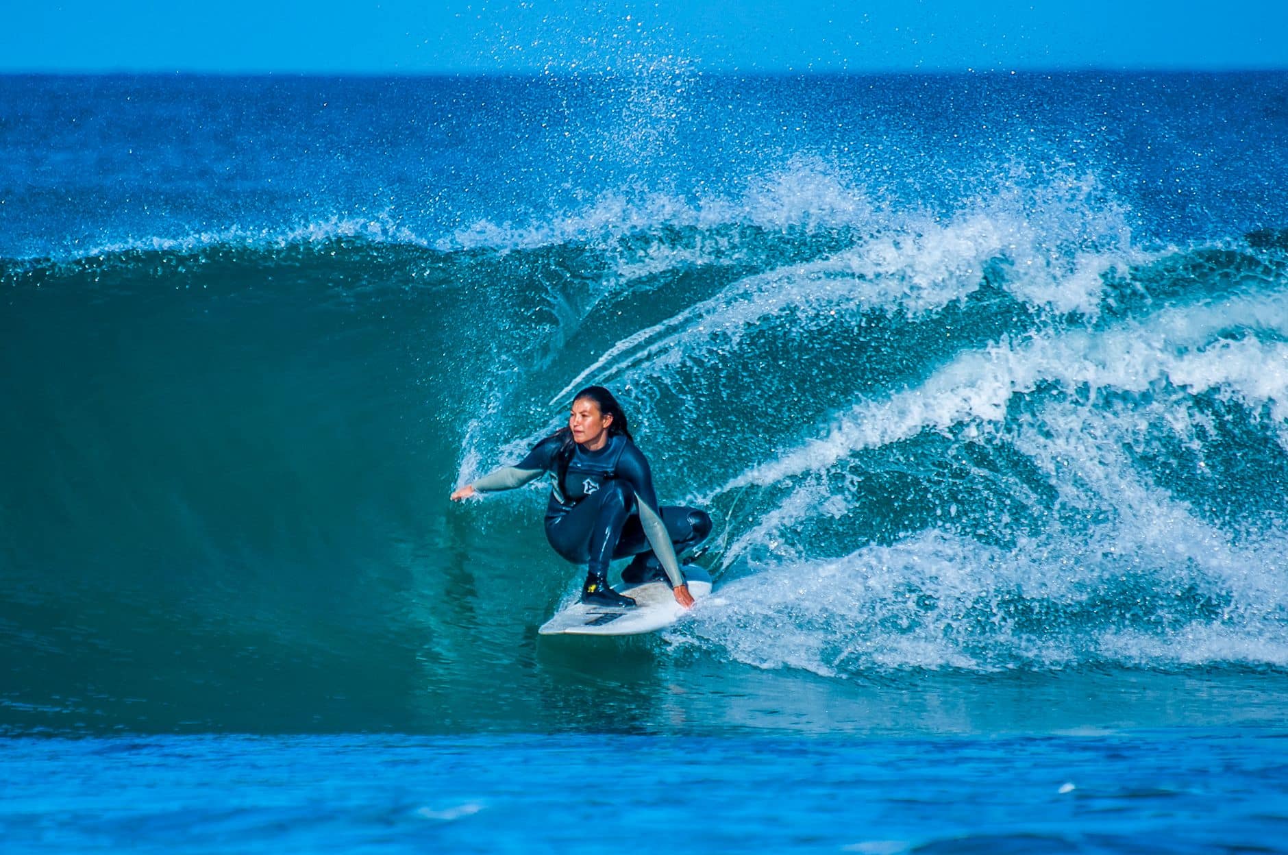 A woman skillfully surfs a large wave at Jeffreys Bay, South Africa.