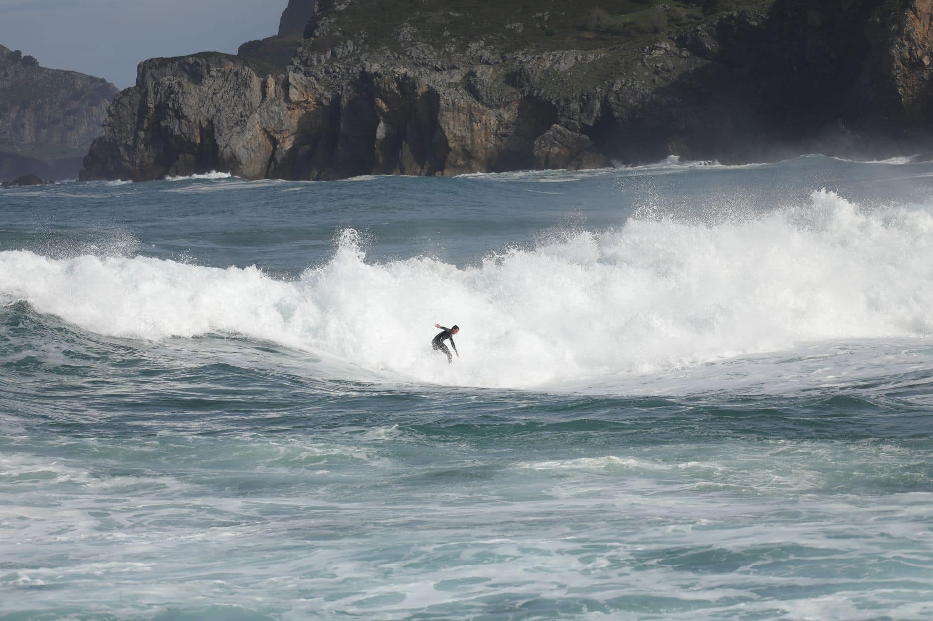 Experience the thrill of surfing on powerful waves near rocky cliffs. Embrace the surfing lifestyle along a dramatic coastline.