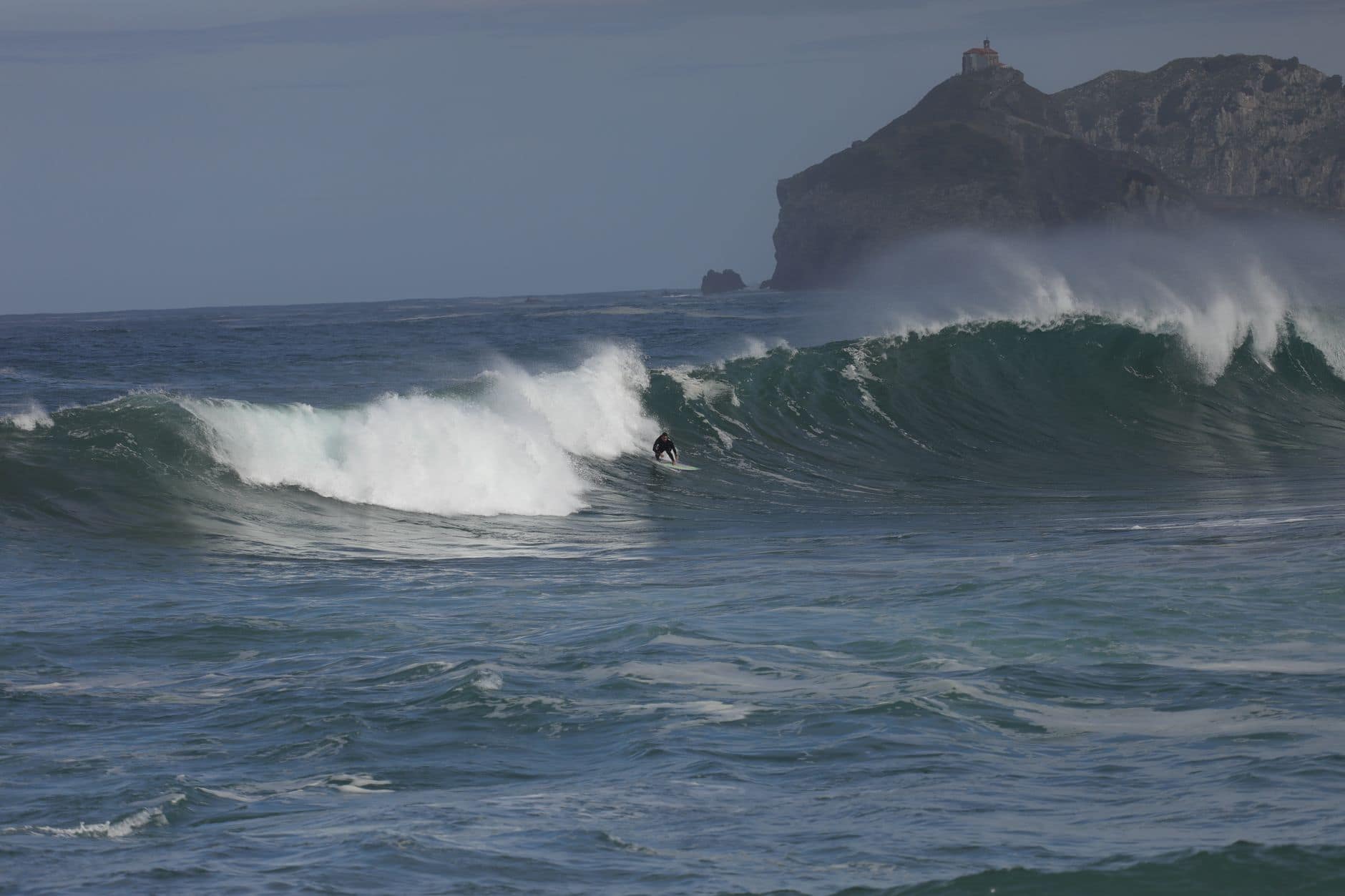 A surfer skillfully riding waves off the coast of Bakio, Bizkaia, highlighting the vibrant surf culture.