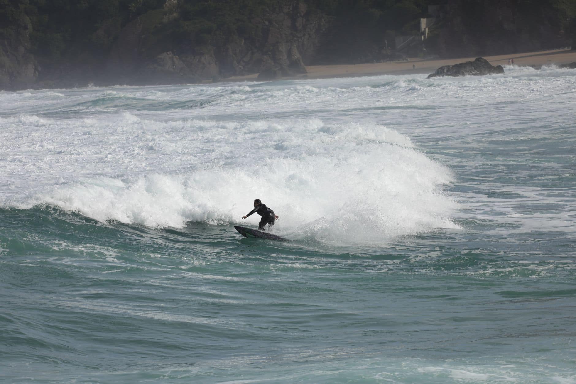 A lone surfer expertly conquers waves at Bakio Beach, Spain, showcasing skill and surfing culture.