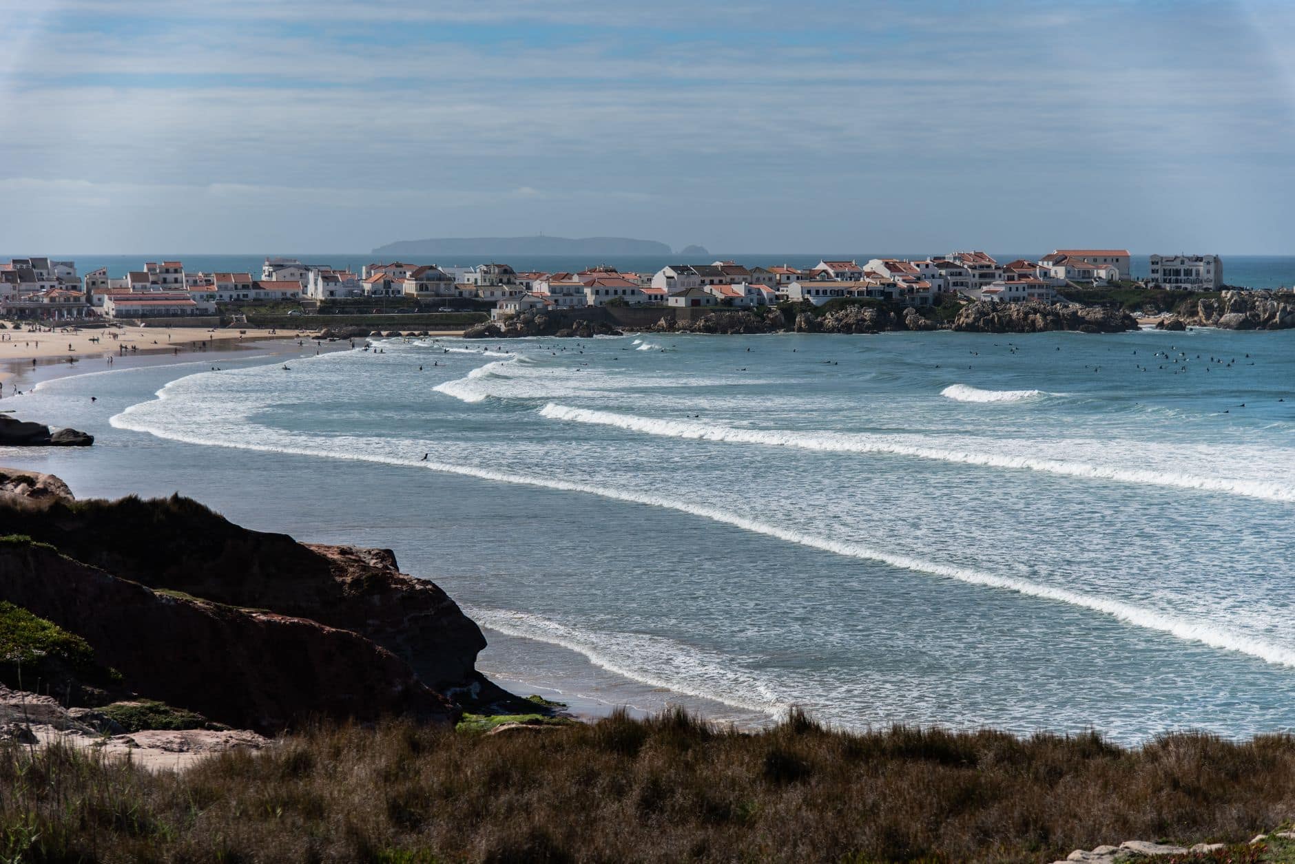 Picturesque view of Peniche's coastline with waves crashing and houses by the Atlantic.