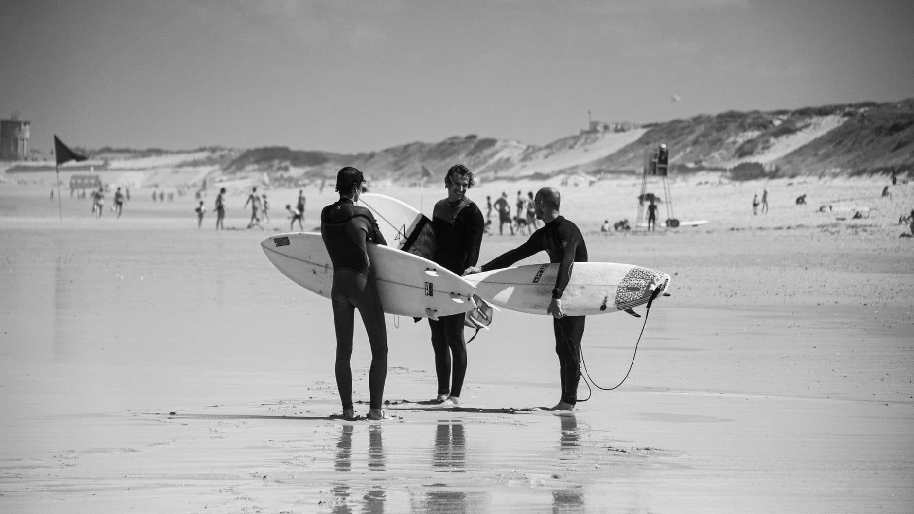 Black and white image of surfers with surfboards at Capbreton beach, France.