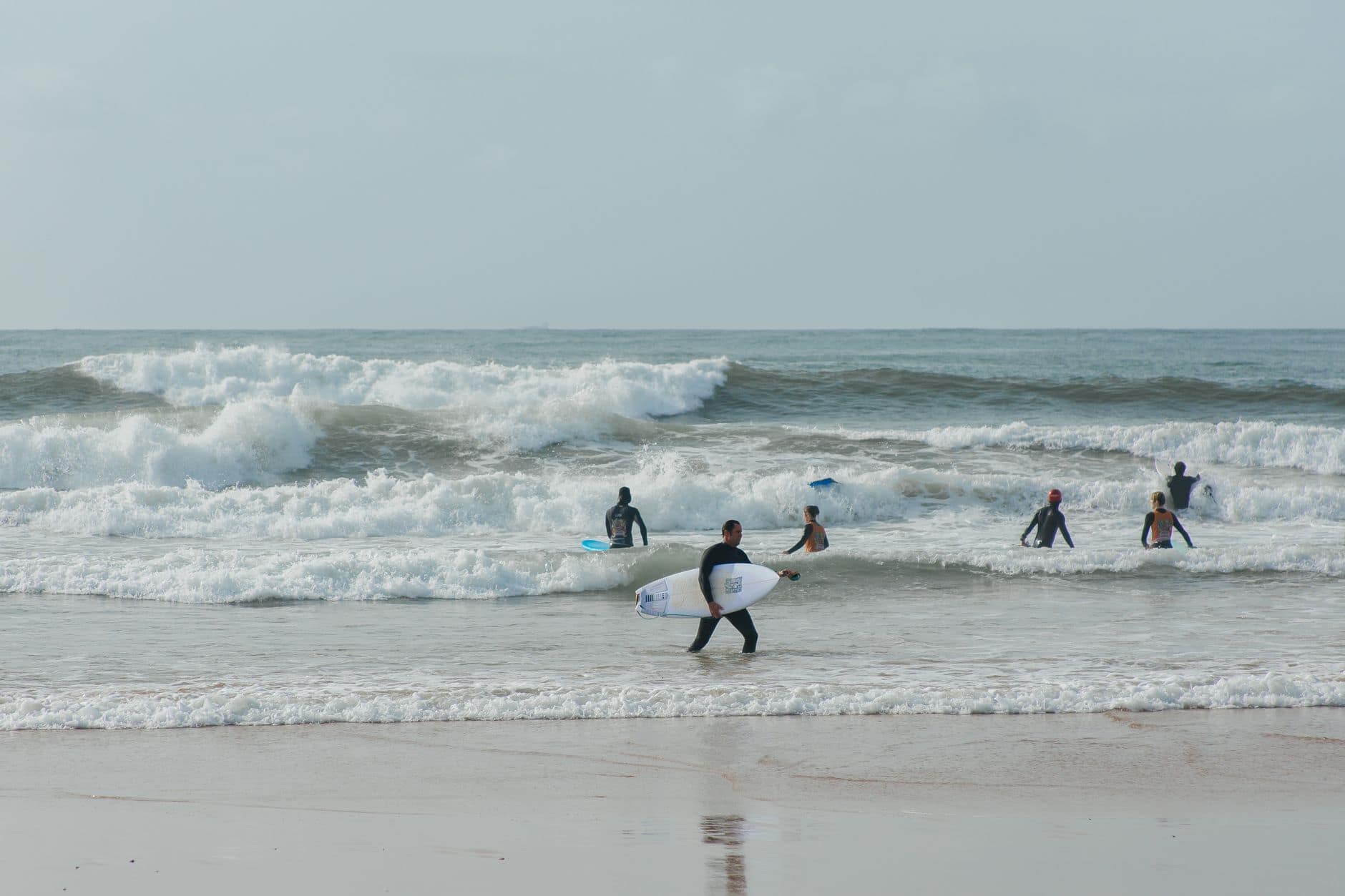 A group of surfers enjoying the waves on a sunny day at the beach.