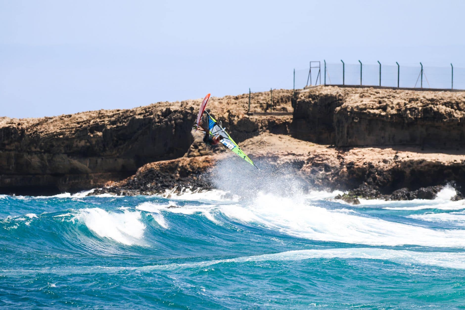 Experience thrilling windsurfing action against stunning rocky cliffs in Spain's Canary Islands.
