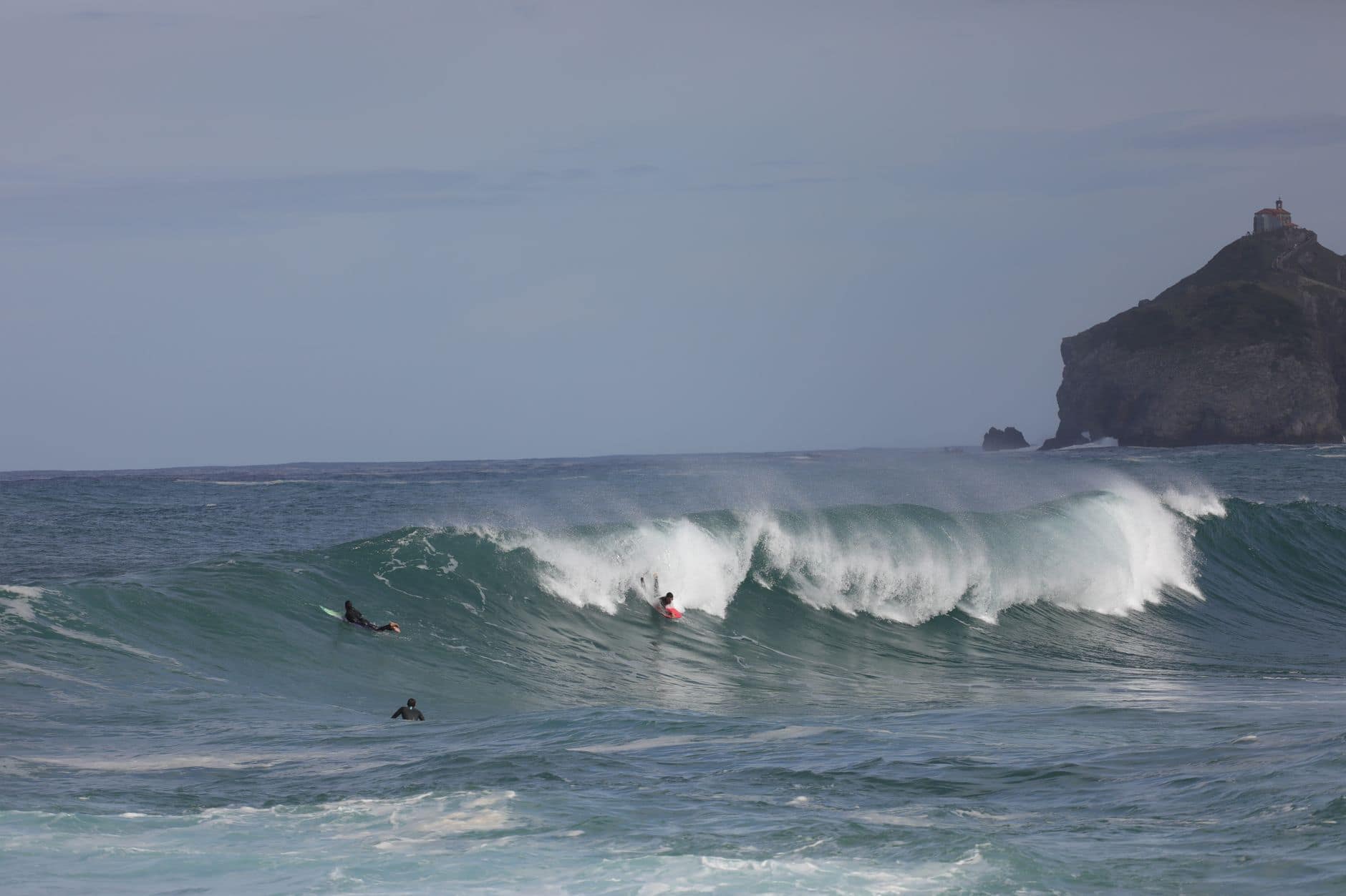 Surfers ride thrilling waves at Bakio Beach, a renowned spot in Bizkaia, showcasing surf culture.