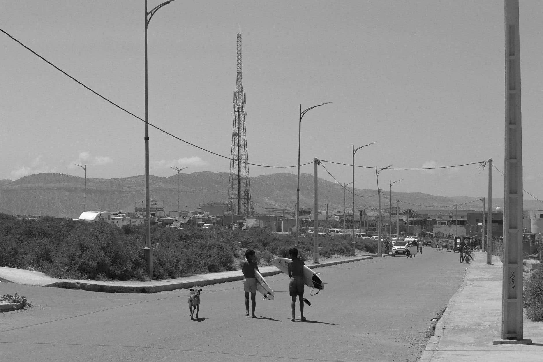 Monochrome view of surfers walking with their dog in Imsouane, Morocco.