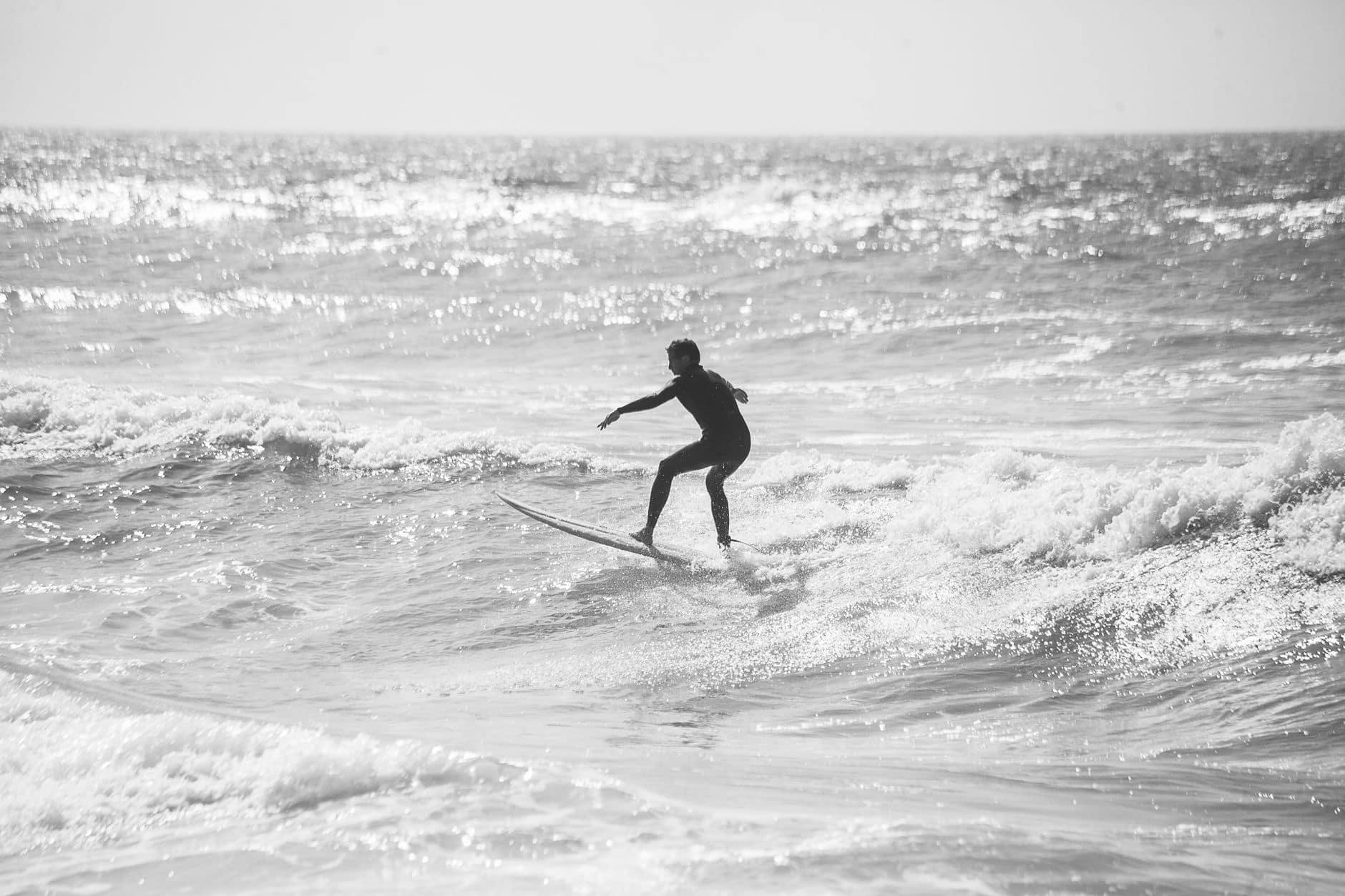 Silhouette of a surfer riding waves in Ericeira, Portugal, in stunning black and white.
