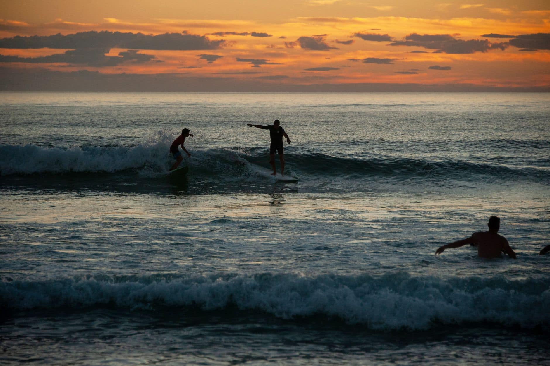 Surfers catching waves at sunset in Seignosse, France. Scenic evening by the ocean.