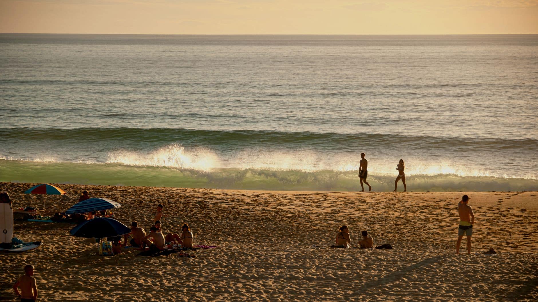 People enjoying a relaxing evening by the sea at Seignosse Beach, France, during sunset.