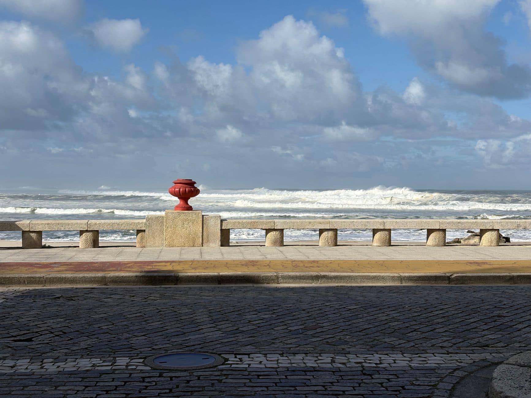 A scenic view of the seaside in Vila Praia de Âncora, Portugal, featuring a red fire hydrant and a wave-battered shoreline.